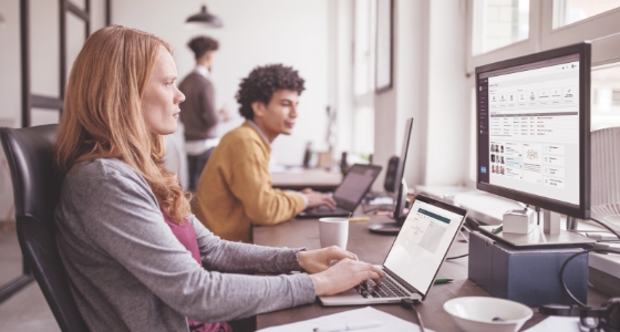 Vrouw met een computer met twee schermen. Op het ene zie je het LanguageWire-Platform, op het andere LanguageWire Translate