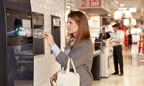 Femme devant une récupératrice automatique de déchets TOMRA 