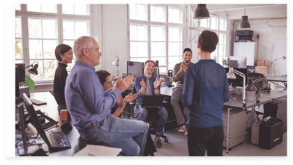 A group of employees listening and clapping to another colleague